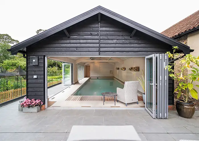 External view from the end of a heated pool lookign through opened bifold doors